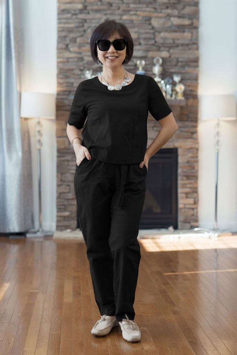 Woman wearing black cotton linen set with short sleeves and straight-leg pants indoors