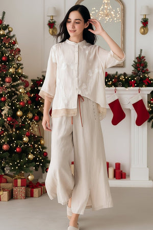 woman wearing 100% cotton linen Tuscany two-piece set with sheer embroidered top and wide-leg trousers in festive Christmas room