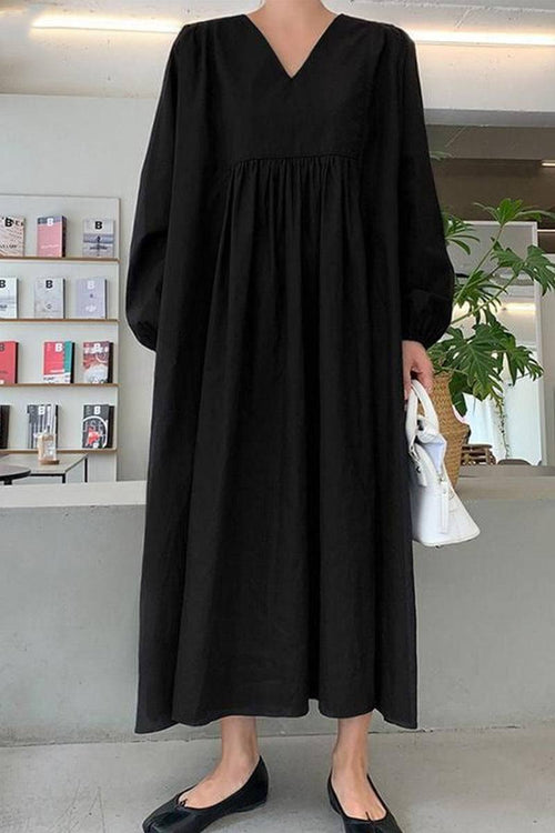 Black midi long sleeve spring dress with V neckline and loose fit, styled with flats and white handbag.