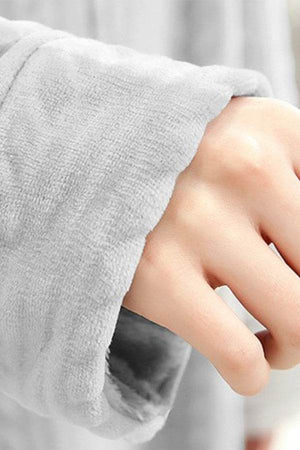 Close-up of a hand in the soft, thick cuff of a stylish flannel nightgown sleeve