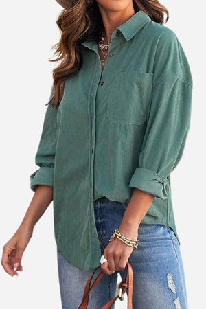 woman wearing sleek suede oversized button-down shirt in green with rolled cuffs and ripped blue jeans