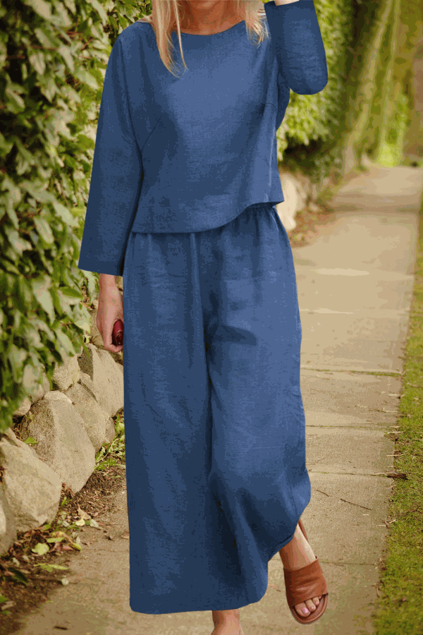 Woman wearing a loose solid color two-piece set with long sleeves and wide-leg pants in blue walking outdoors