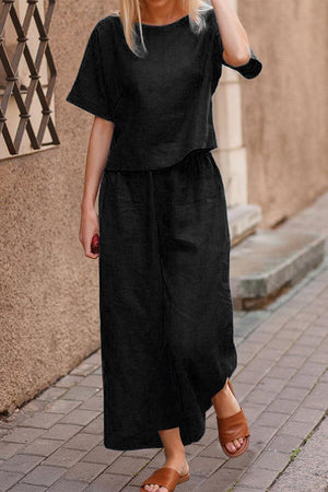 Woman wearing black loose fit co-ord set with short sleeves and wide-leg pants walking outdoors