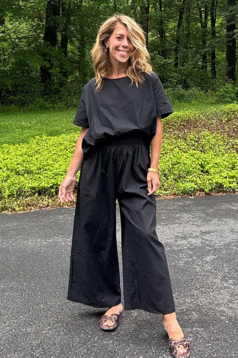 Woman wearing black loose fit co-ord set with wide short sleeves and wide-leg trousers outdoors