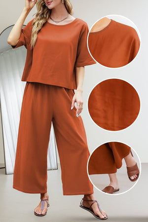 Rust-colored loose fit co-ord set with relaxed short-sleeve top and wide-leg pants, breathable fabric, styled with sandals