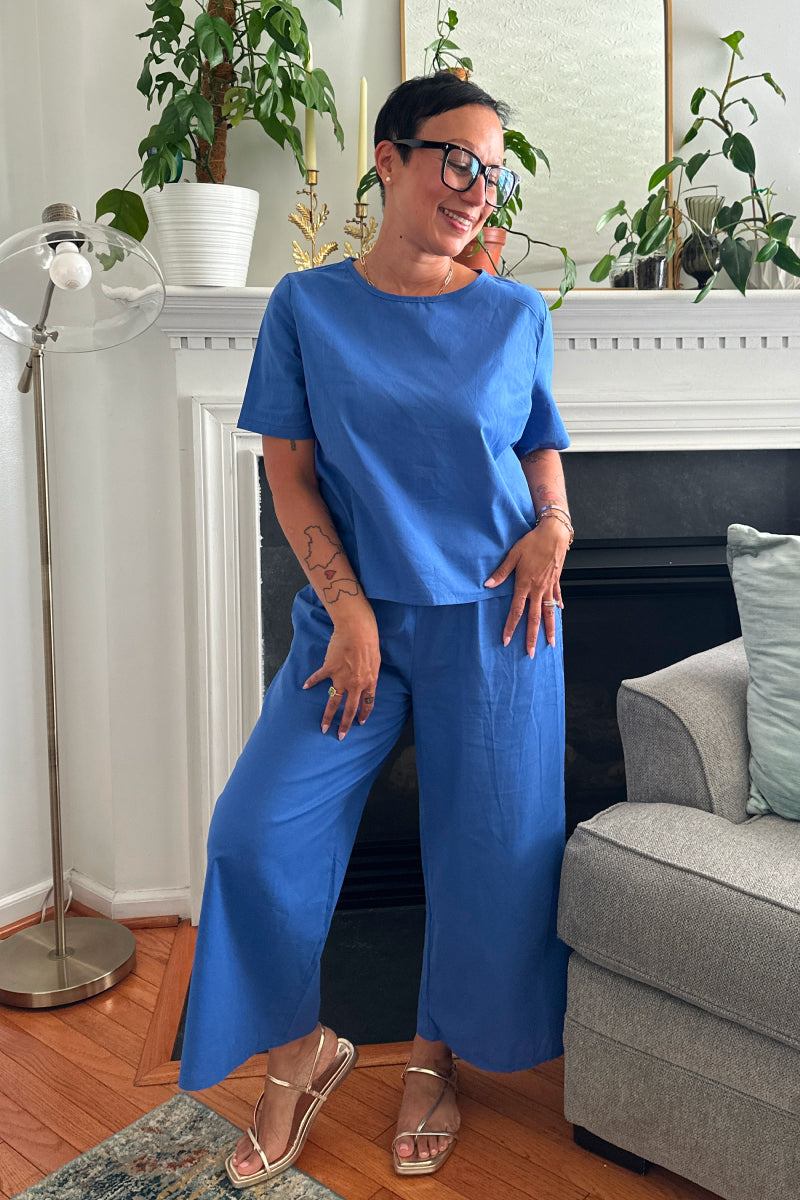Woman wearing a blue loose fit co-ord set with short sleeves and wide-leg trousers in a cozy living room.