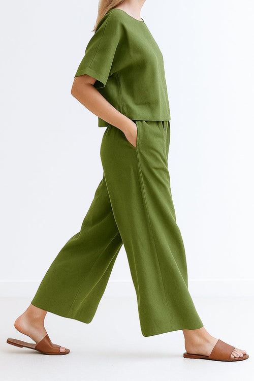 Woman wearing olive green loose fit co-ord set with short sleeves and wide-leg pants walking with brown sandals