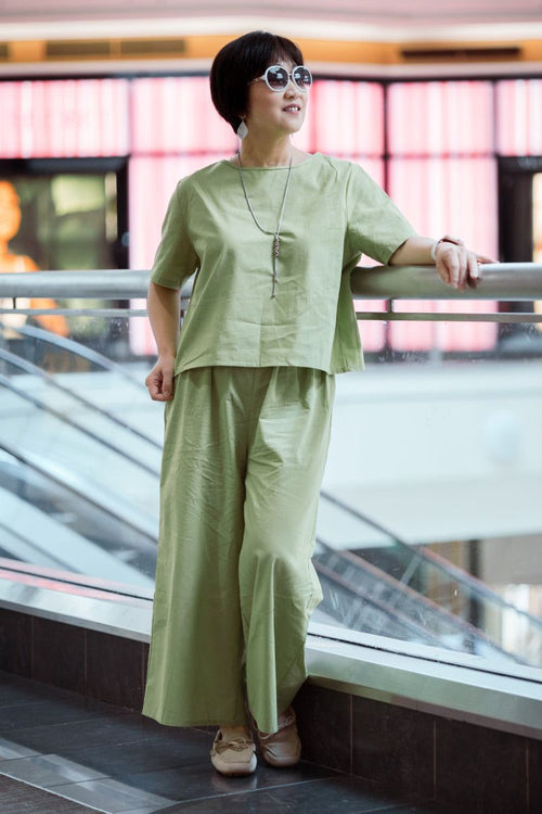 woman wearing light green loose fit co-ord set with short sleeves and wide-leg pants standing indoors