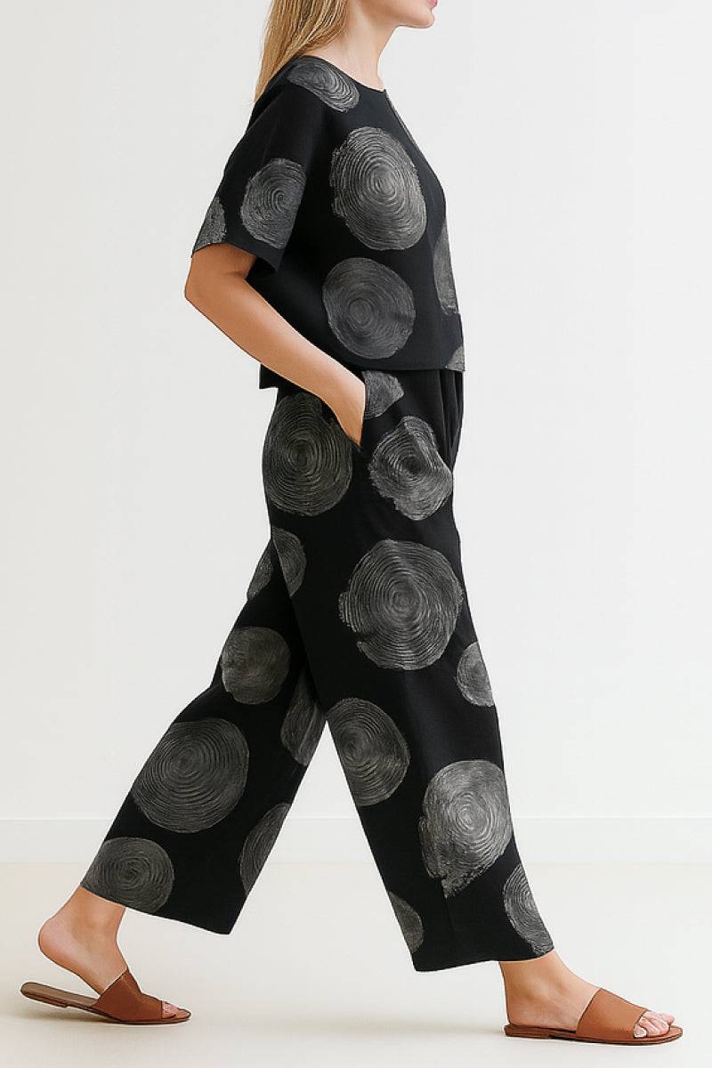 Woman wearing black loose fit co-ord set with large gray circular patterns, wide-leg pants, and relaxed short-sleeve top
