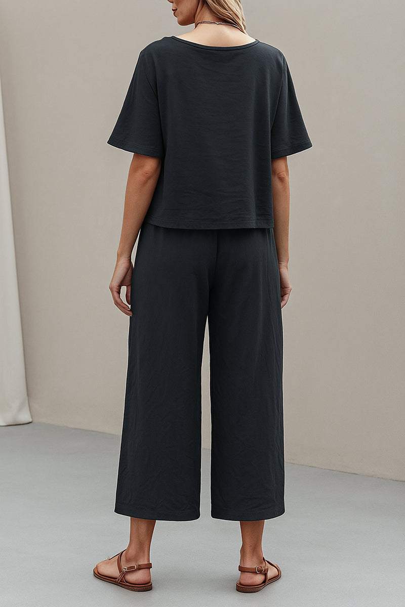 Back view of a woman wearing a black loose fit co-ord set with wide-leg pants and relaxed short-sleeve top.