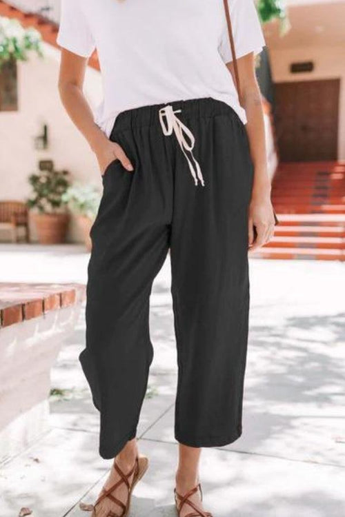 Woman wearing black relaxed fit straight pants with drawstring waist and white t-shirt outdoors