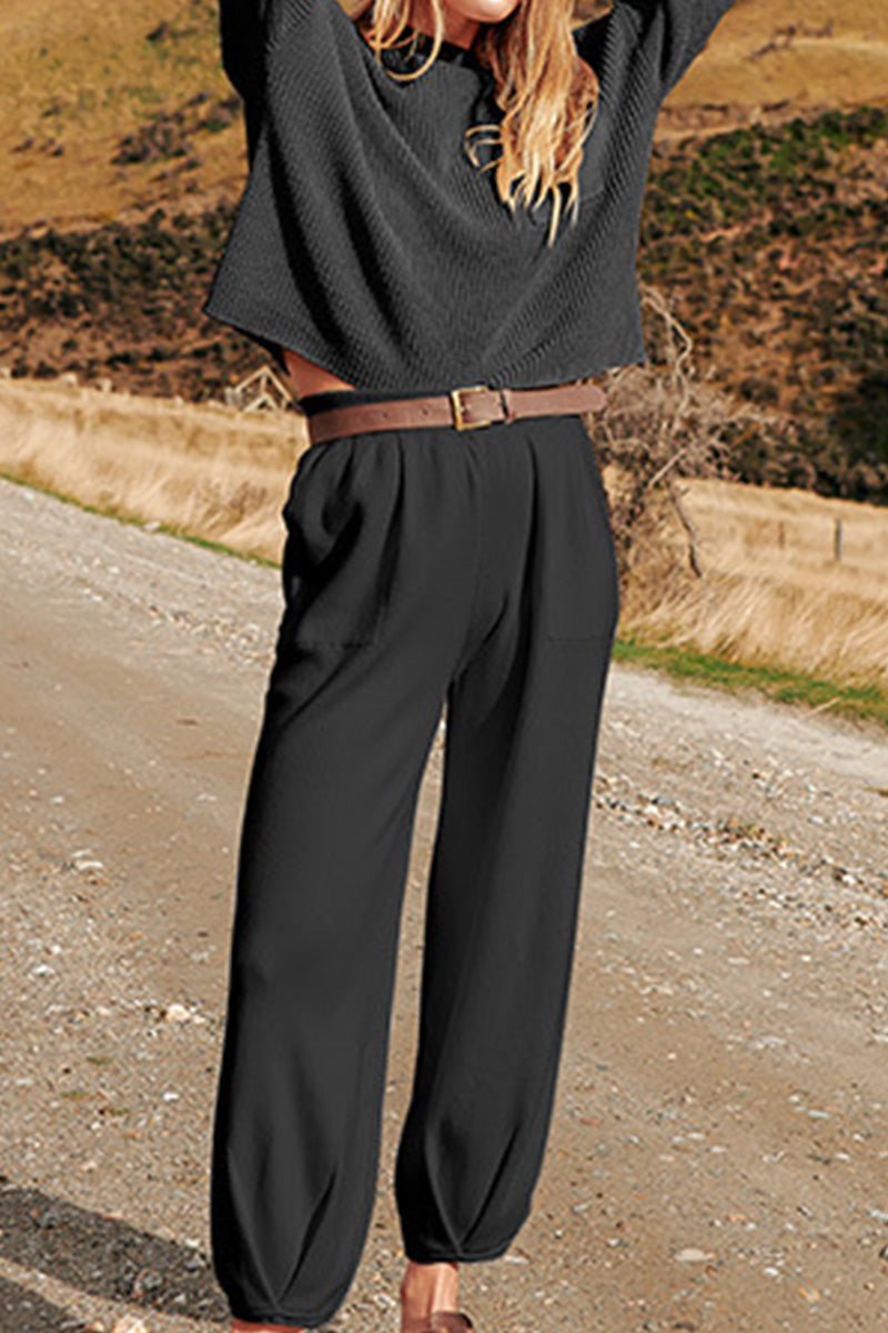 Woman wearing European minimalism relaxed black sweater top and trouser set outdoors