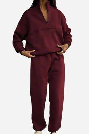 Woman wearing a maroon cotton-blended two-piece tracksuit with high collar and deep zipper front.