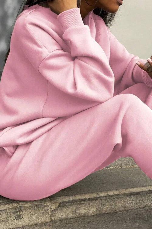 Woman wearing a pink cotton-blended two-piece tracksuit sitting on stone steps