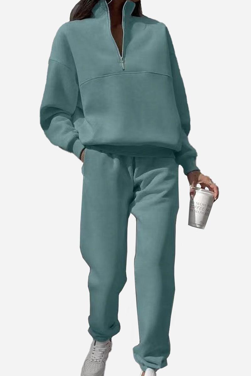 Woman wearing blue cotton-blended two-piece tracksuit with high collar and zipper, holding coffee cup