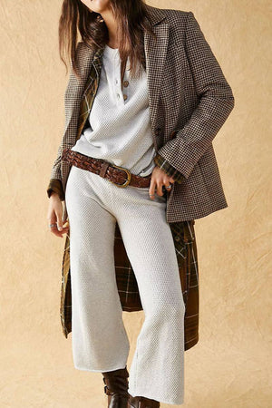 Woman wearing multi-weather comfort two-piece oversized set with cropped wide pants and relaxed top layered with checkered blazer and brown belt