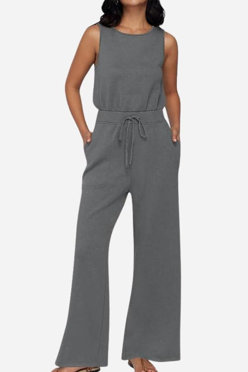 Woman wearing a gray sleeveless wide leg pants jumpsuit with drawstring waist and pockets