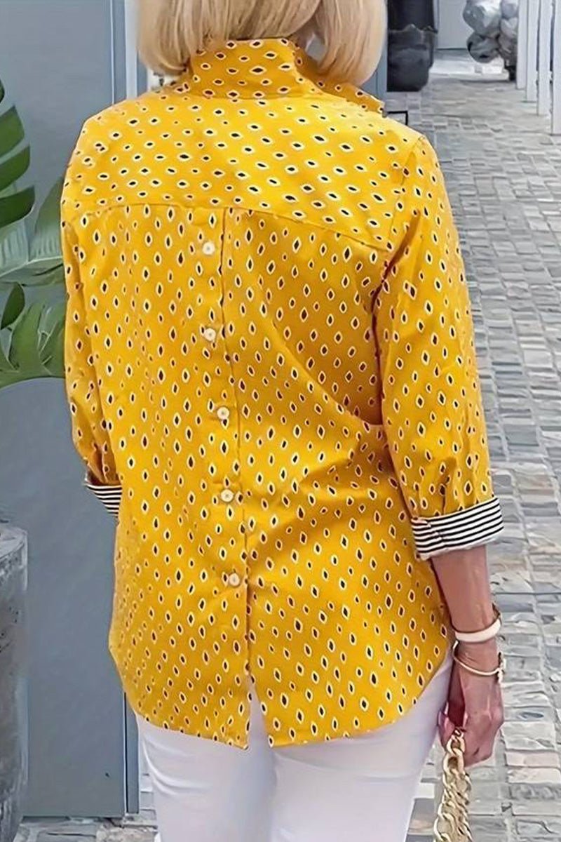 Back view of Boho Chic Resort Blouse in yellow with polka dots and striped cuffs, worn with white pants.