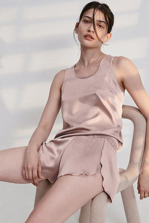Woman wearing blush pink Mulberry Silk Tank & Shorts Set sitting on beige chair in soft natural light