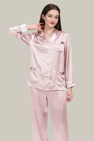 Woman wearing light pink long sleeve silk pajamas set with button-up top and relaxed fit pants