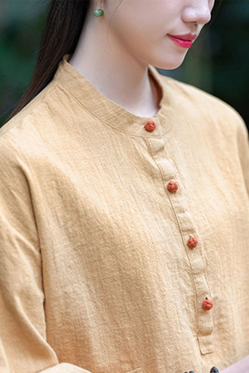 Woman wearing a beige ramie linen and cotton blouse with a stand collar and wooden buttons
