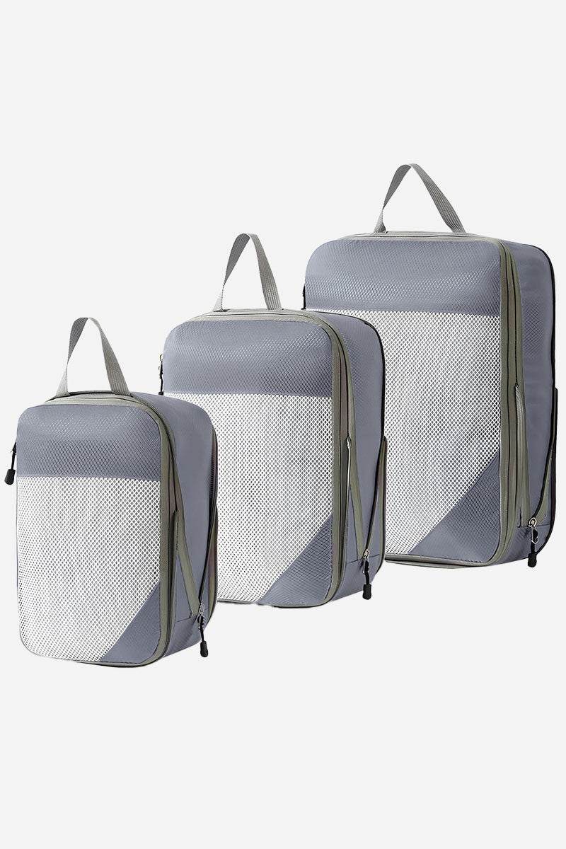Set of three grey space-saving compression packing organizers with handles and mesh fronts for travel and suitcase organization