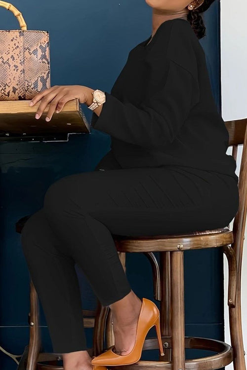 Woman wearing black cotton two-piece set vibrant comfortable outfit with orange high heels sitting on a wooden chair