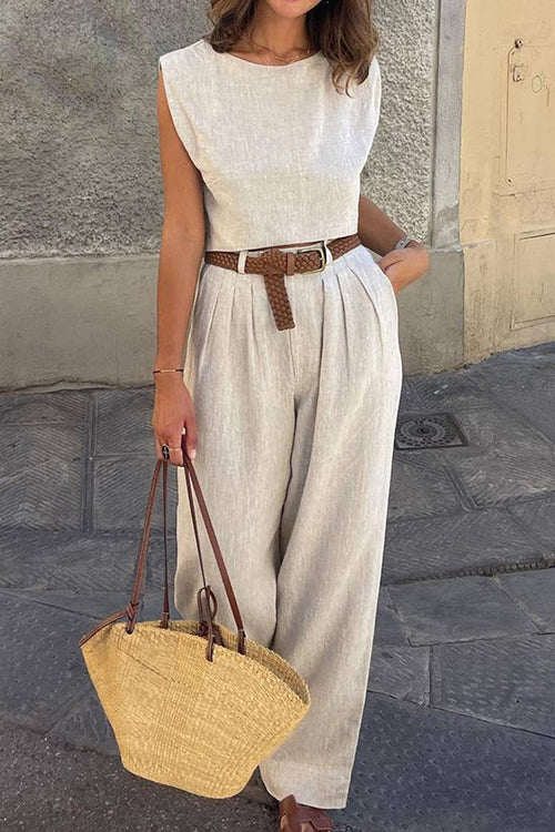 Woman wearing cotton-linen blend sleeveless crop top and wide-leg pants summer outfit with brown belt and straw handbag