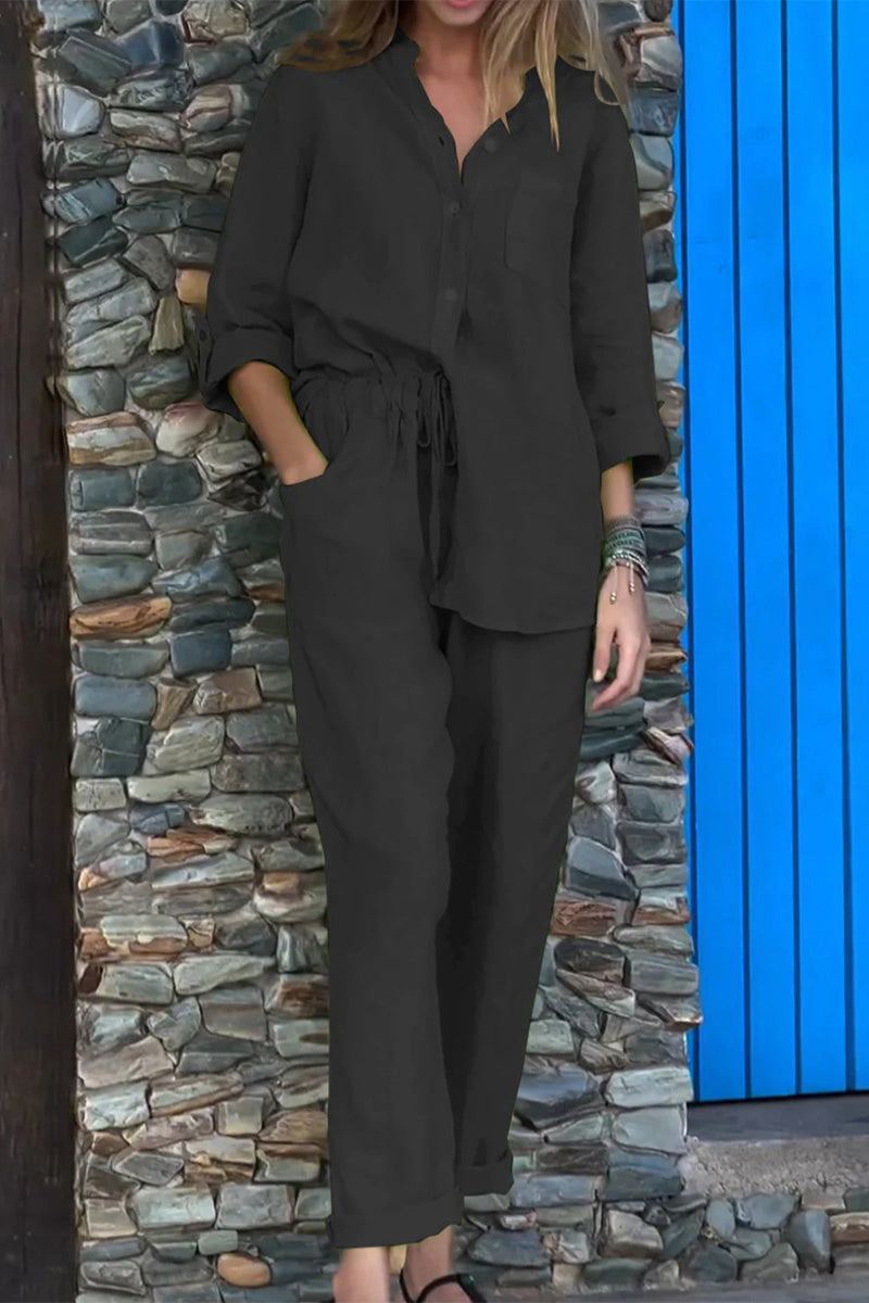 Woman wearing a black Casual Chic Two-Piece Set with a relaxed fit, long sleeves, and drawstring pants next to a stone wall and blue door.
