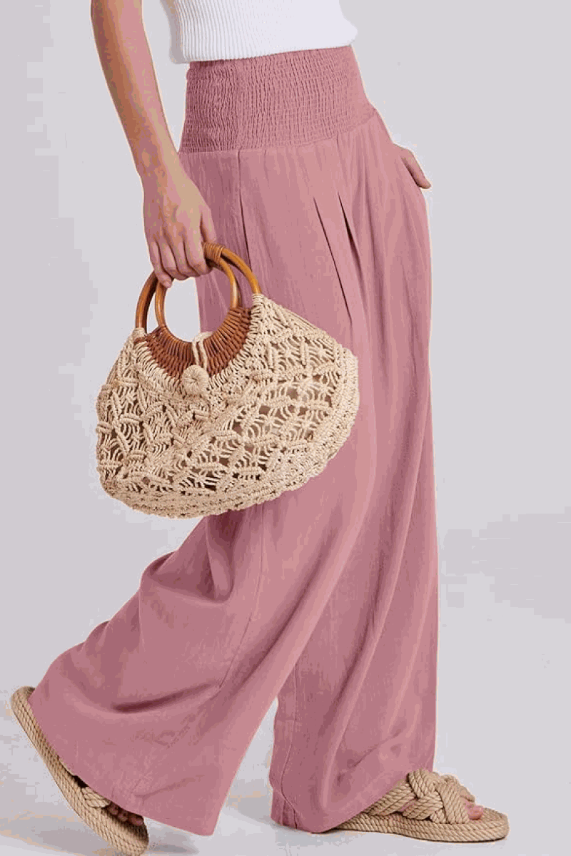 Woman wearing oversized linen leaved-in set with flowy pink palazzo pants and woven handbag