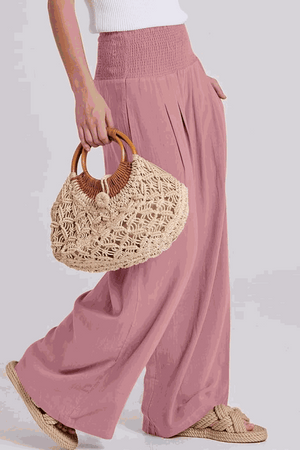 Woman wearing oversized linen leaved-in set with flowy pink palazzo pants and woven handbag