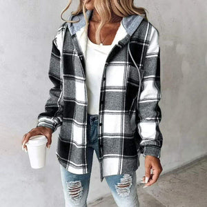 Woman wearing a Highland Plaid Shacket with black, white, and gray plaid, hood, button front, and soft fleece lining, paired with ripped jeans and holding a coffee cup.