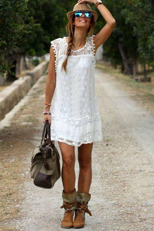 Woman wearing white pom pom lace mini dress with sleeveless design outdoors