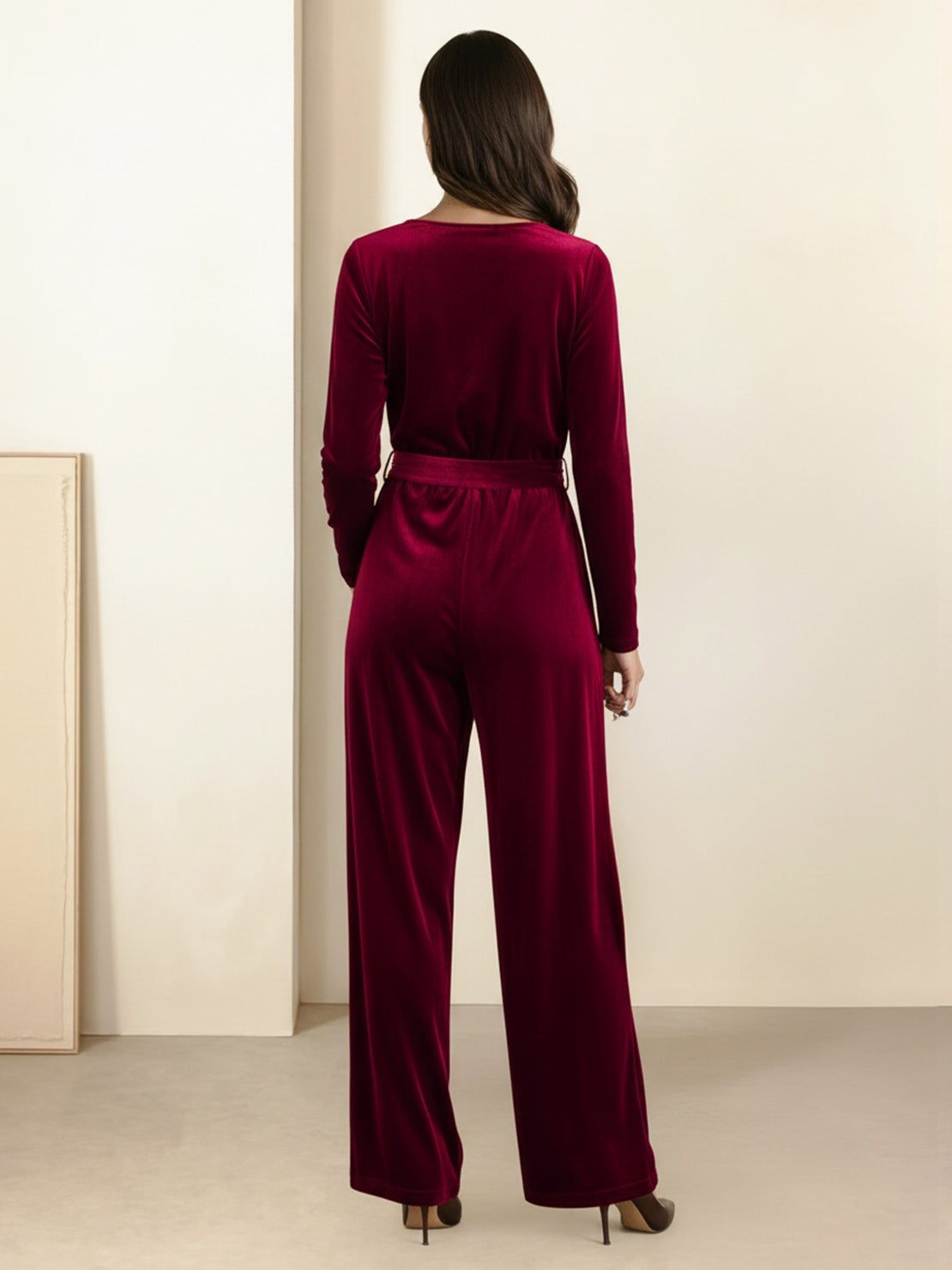 Woman wearing a deep V-neck velvet suit with long sleeves, removable waist tie, and wide-leg pants with side pockets