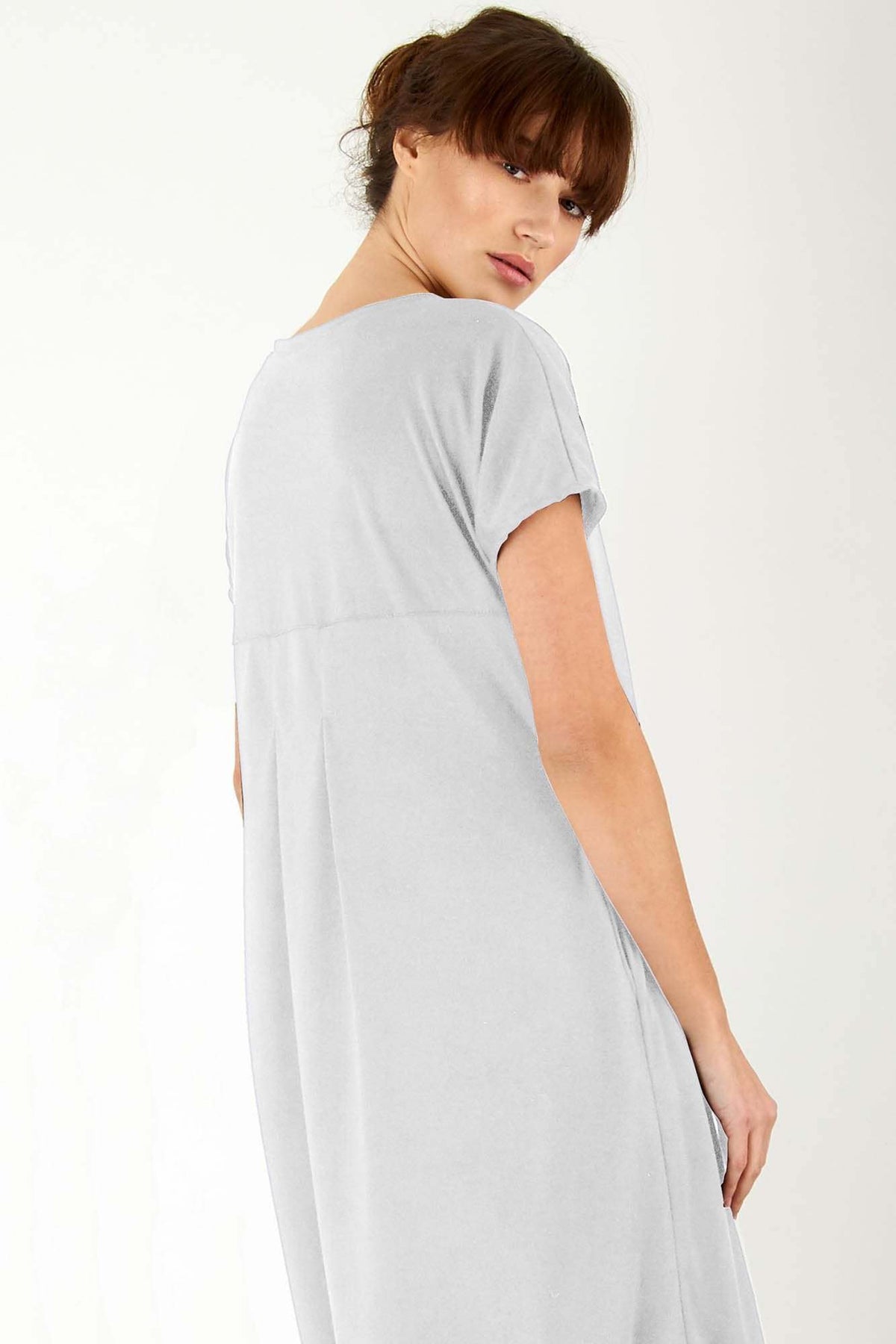 Woman wearing a light grey side slit maxi dress with pockets and rolled sleeves