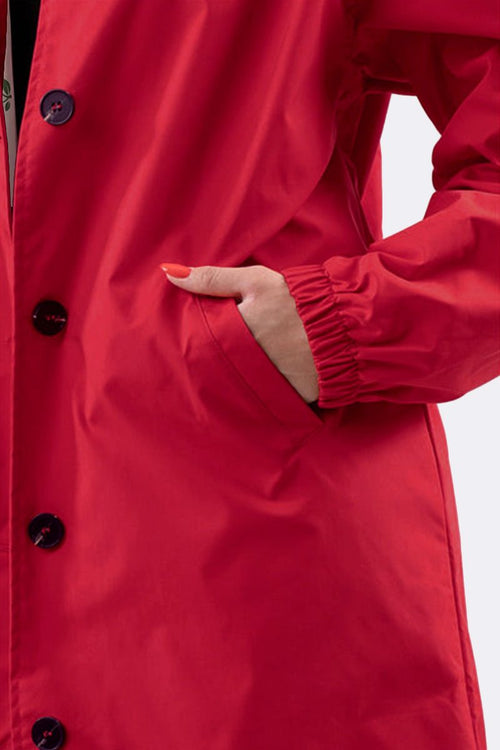 Close-up of a red water resistant oversized windbreaker with elastic cuff and front pocket detail