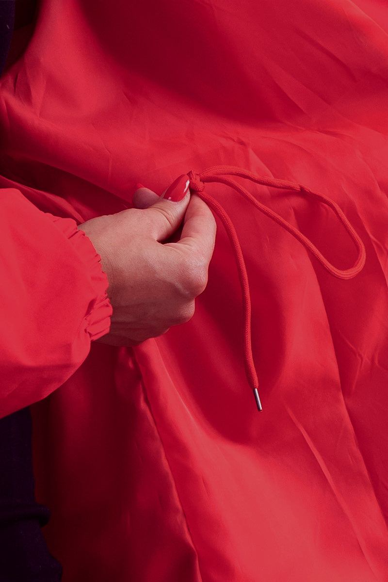 Close-up of adjustable drawstring on red water-resistant windbreaker jacket