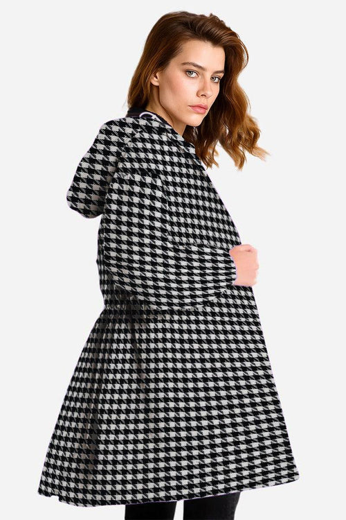 Black and white houndstooth oversized water-resistant windbreaker jacket with hood worn by woman