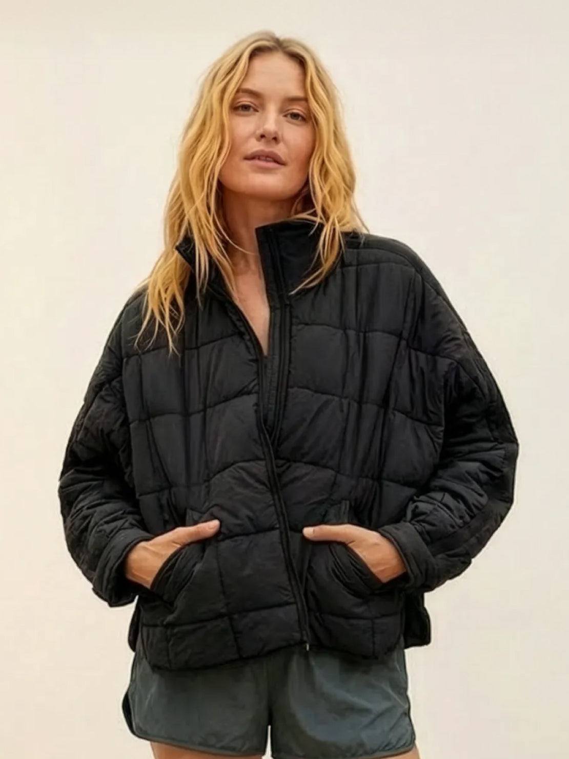 Woman wearing a black lightweight puffer travel jacket with front pockets and zipper closure