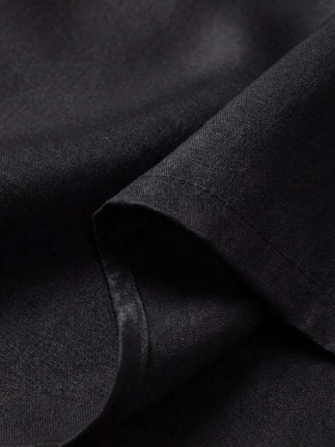 Close-up of breathable, silky soft fabric used in the asymmetrical two-piece trouser set in black color
