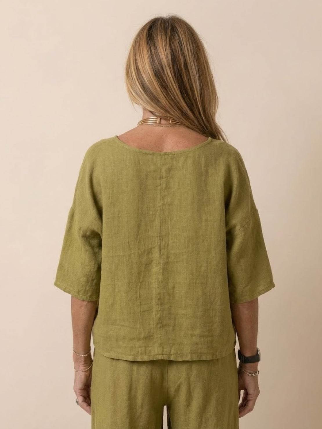 Back view of woman wearing olive green short-sleeved pullover and wide trouser matching set