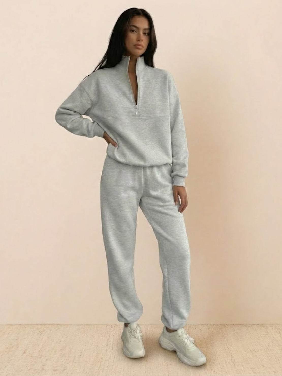 Woman wearing a stylish cotton-blended two-piece tracksuit with high collar and zipper, showcasing comfy athleisure fashion.