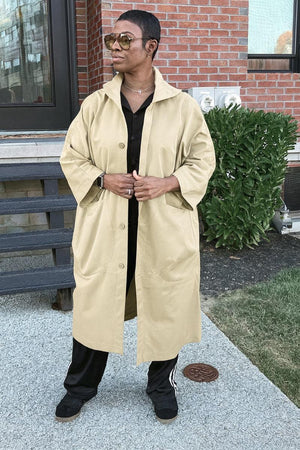 One size fits all oversized beige windbreaker jacket with waterproof design, snap-button closure, attached hood, and large front pockets.