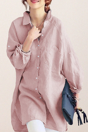Woman wearing oversized pink linen shirt holding blue clutch bag