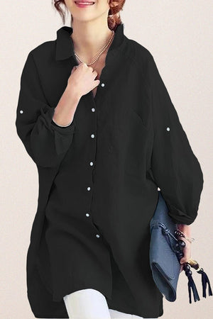 Black oversized linen shirt with relaxed fit and button details worn with white pants and blue clutch