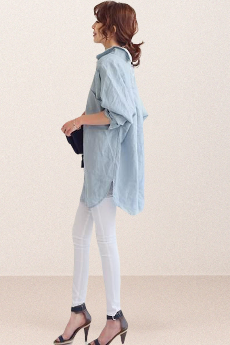 Side view of woman wearing oversized linen shirt in light blue with rolled sleeves and white pants