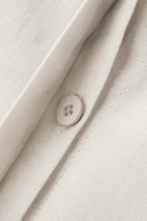 Close-up of beige oversized 100% cotton shirt fabric with button detail