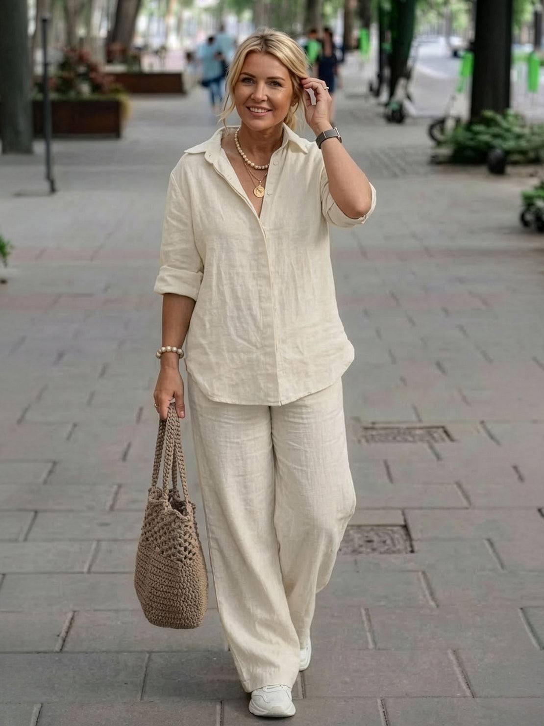 Woman wearing oversized 100% cotton shirt and wide-leg pants co-ord set walking outdoors carrying a woven tote bag