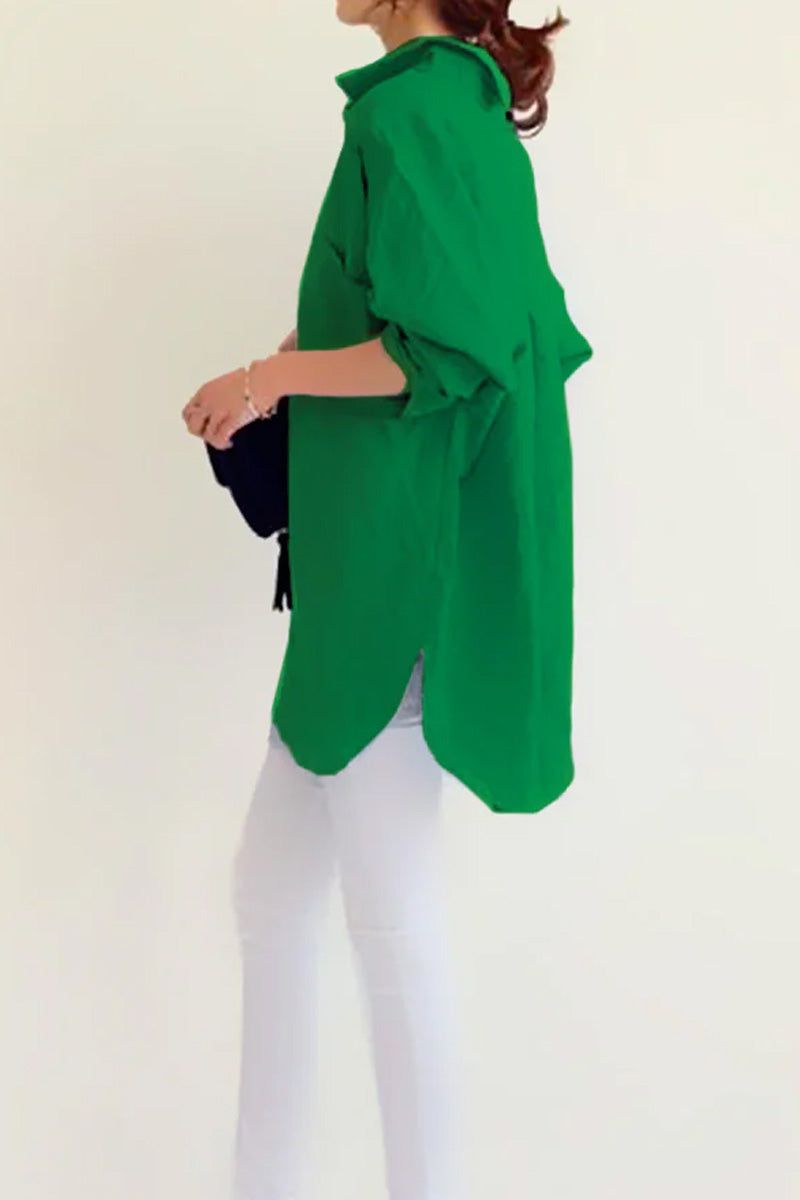 Woman wearing bright green oversized linen shirt with rolled-up sleeves and white pants against white background