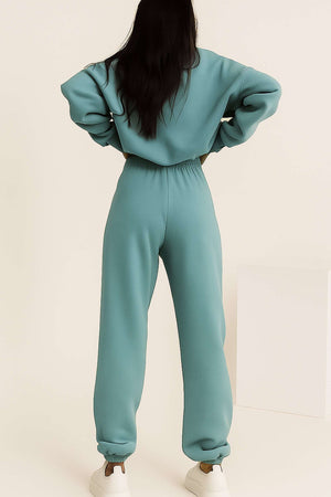 Woman wearing mint green cotton blend tracksuit with elastic cuffs, seen from back